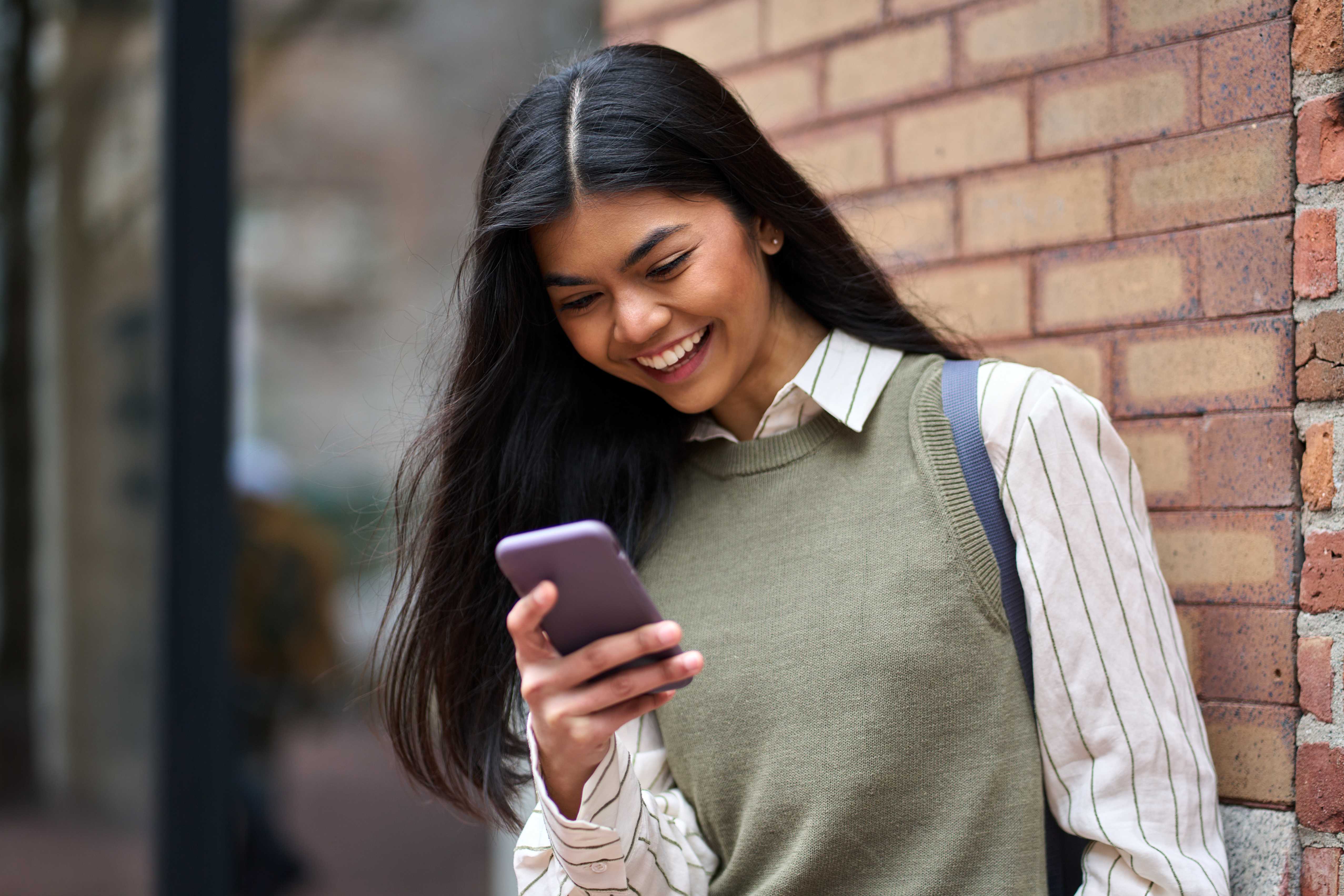 Student smiling while using a language learning app on her smartphone